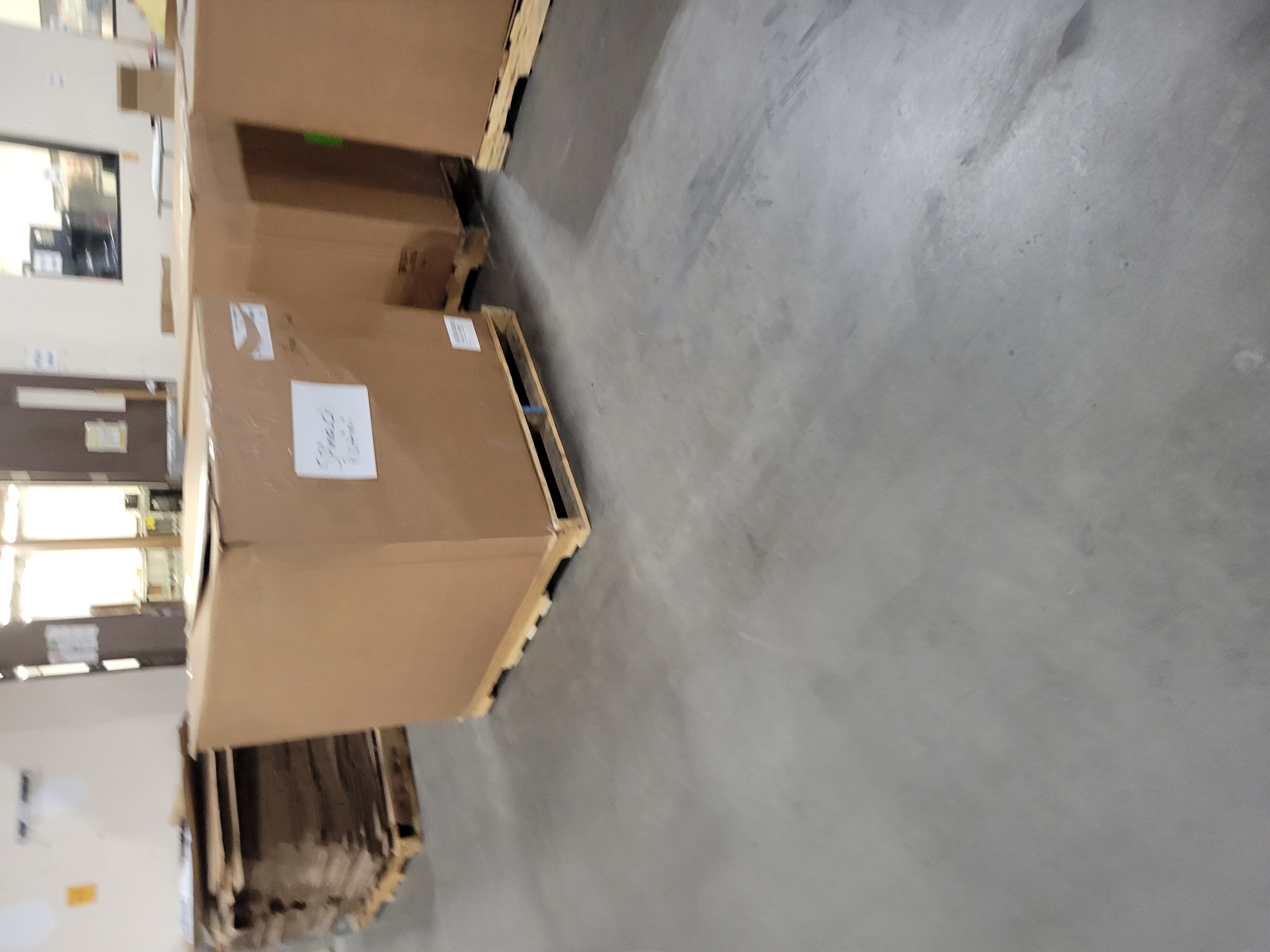 Pallets of cardboard containers with tops on them and a pallet of flattened cardboard behind it. 